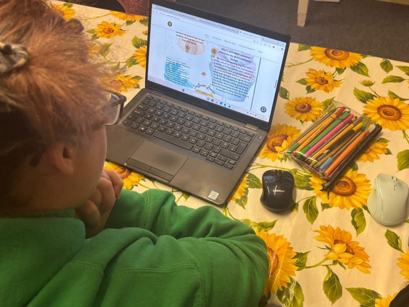 Llun o fenyw o flaen cyfrifiadur yn The Sunflower Lounge